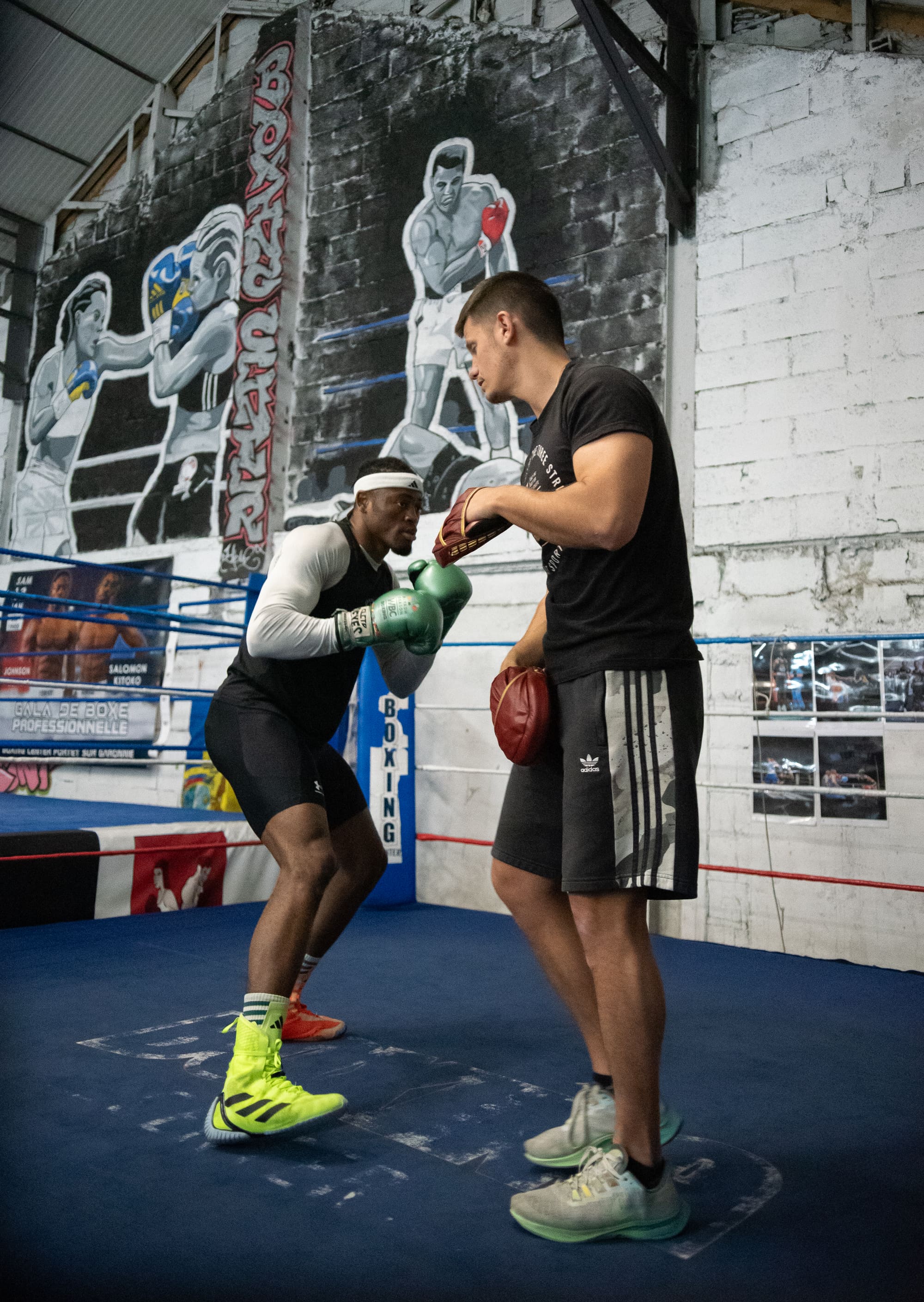 Un coach prépare les gants d'un pratiquant dans le ring, avant le début du travail.